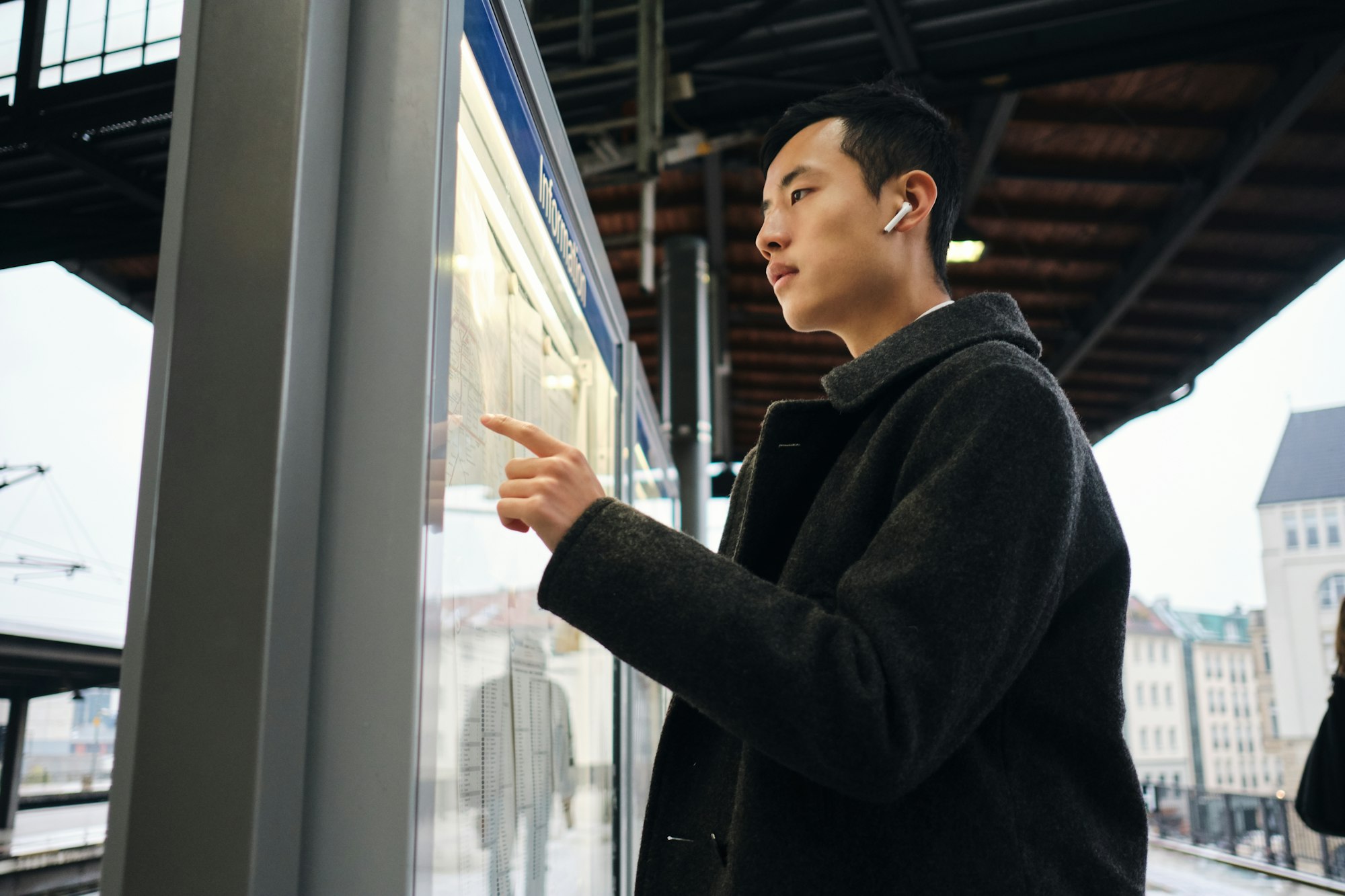 Asian businessman thoughtfully watching timetable of public transport at metro station